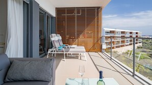 A balcony with a sofa, a table with a wine glass and bottle, and a chair. - Exquisite modern apartment [112] (Lagos)