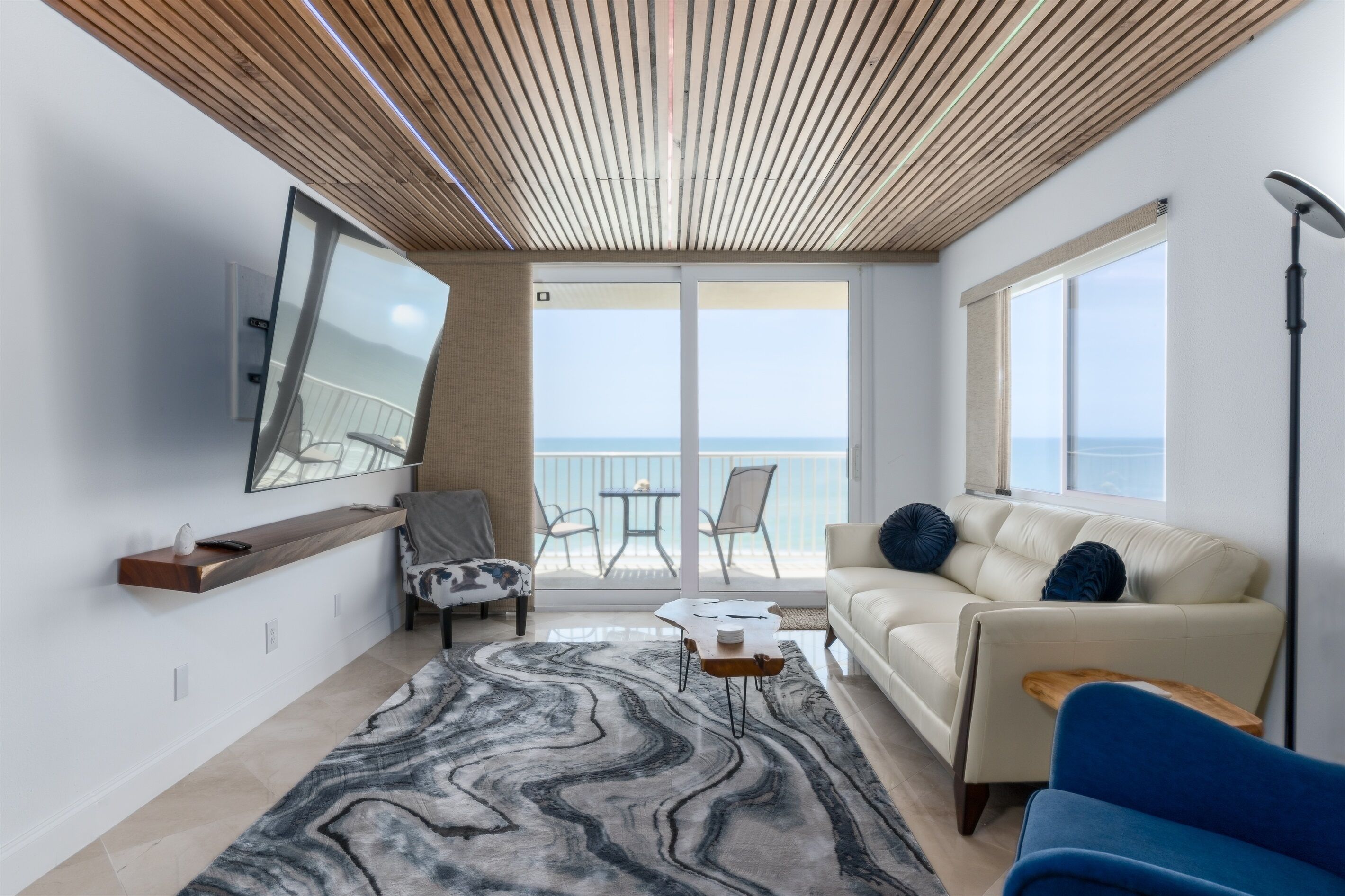 Una sala de estar moderna con un sofá, una mesa de centro y vistas al mar a través de grandes ventanales.