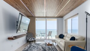 Ein modernes Wohnzimmer mit einer Couch, einem Couchtisch und Meerblick durch große Fenster.