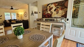 Un coin repas avec une table en bois, des chaises, une plante en pot et un mur orné d’une carte du monde et d’épices.