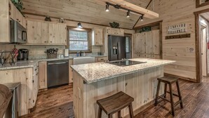 A kitchen with wooden cabinets, granite countertops, a stainless steel refrigerator, and a built-in dishwasher. - Take a Paws - close to downtown, fenced yard, pets (Blue Ridge)