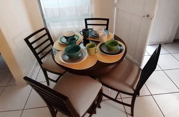 A dining table set with green and white plates, cups, and bowls.