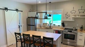 A modern kitchen with a central island, stainless steel appliances, and a dining area with four chairs.
