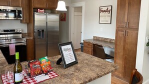 A modern kitchen with stainless steel appliances, wooden cabinets, and a granite countertop. - Surfs Up! Pro Cleaned, Self Check in - Sleeps 14 (Racine)