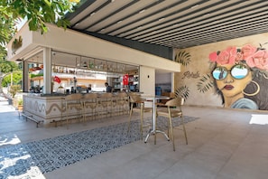 Eine Bar mit Theke, Barhocker und Wandgemälde.