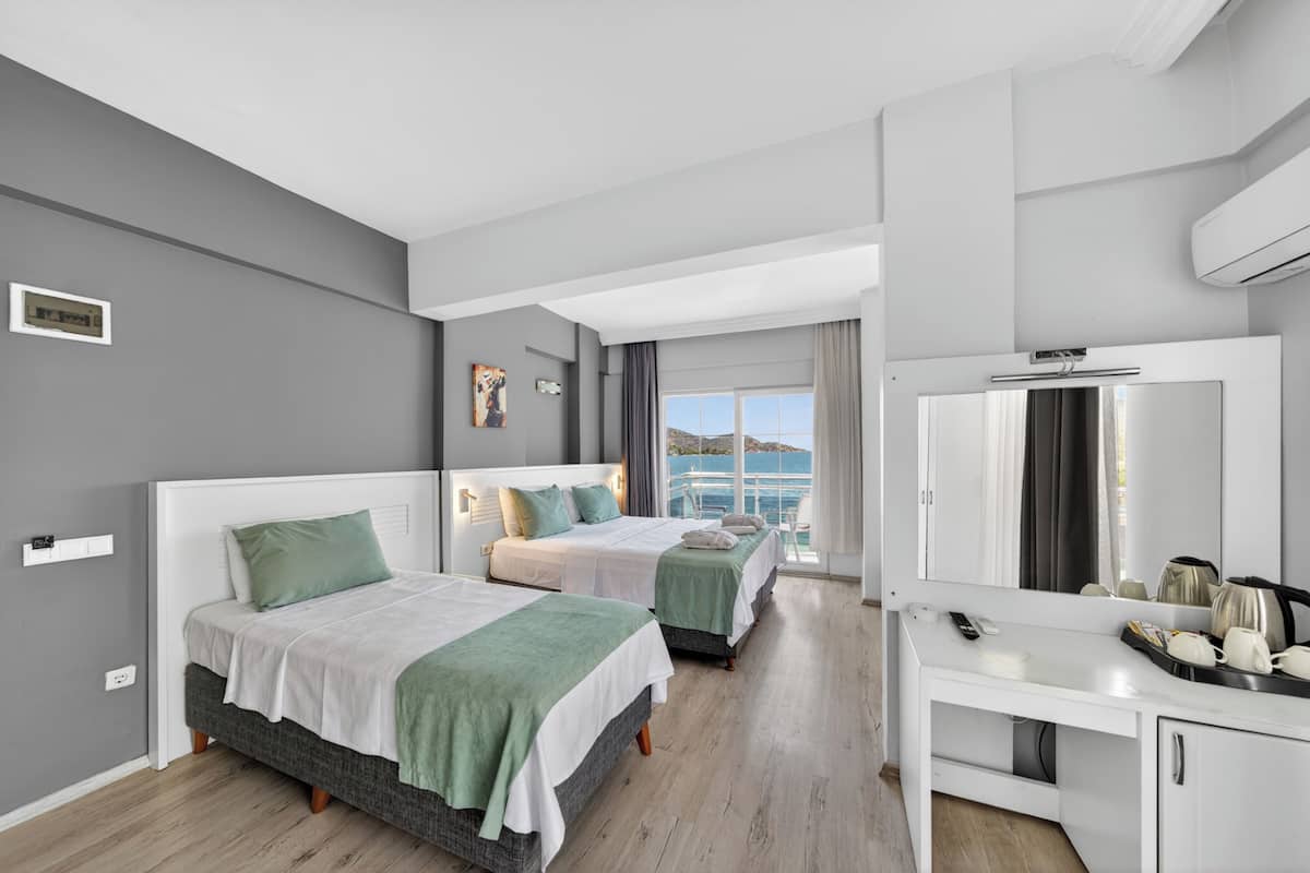 A hotel room with two beds, a desk, and a large window with a view.