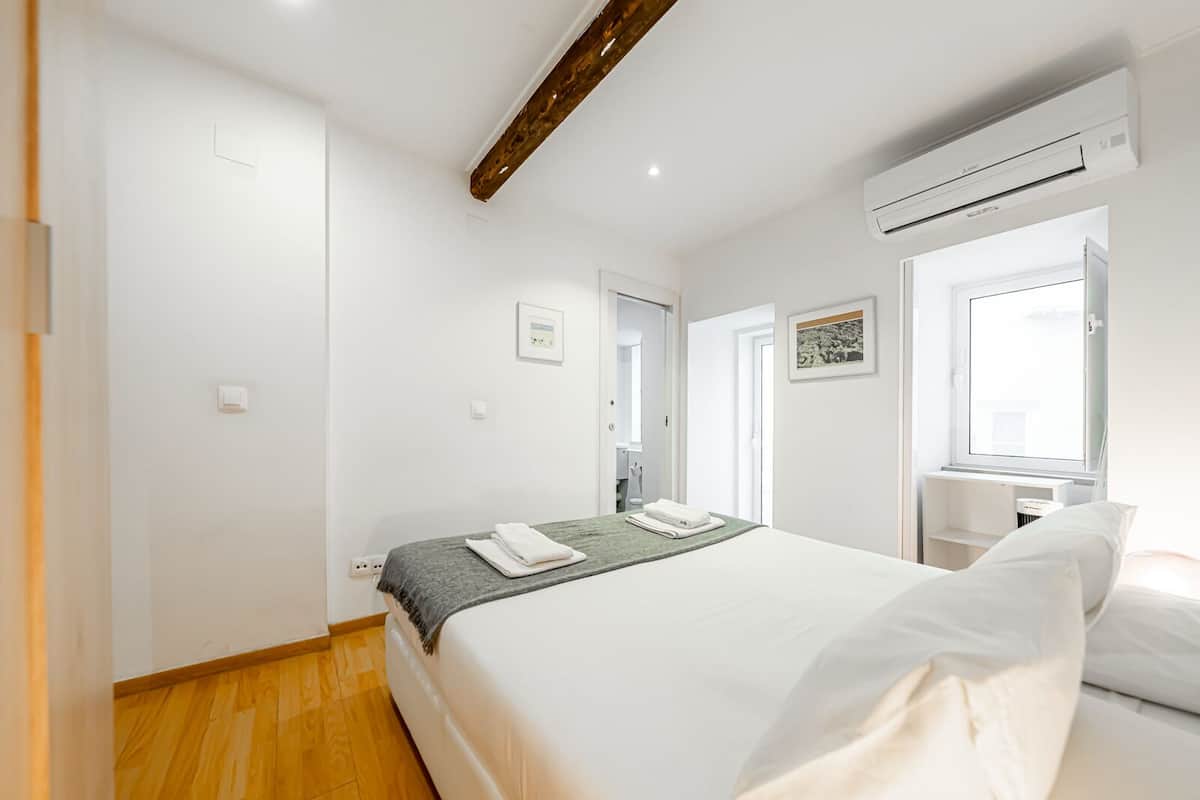 Une chambre d’hôtel équipée d’un lit, d’un bureau, d’un climatiseur et d’une fenêtre.