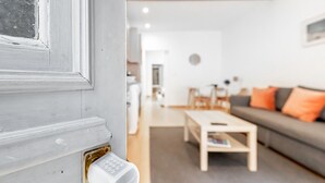 Un salon moderne avec un canapé gris, une table basse et une porte dotée d’un système de verrouillage à clavier.