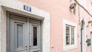 Une porte à deux battants, dotée d’une poignée en laiton et d’une plaque avec le numéro de la maison, de couleur bleue, placée au-dessus.