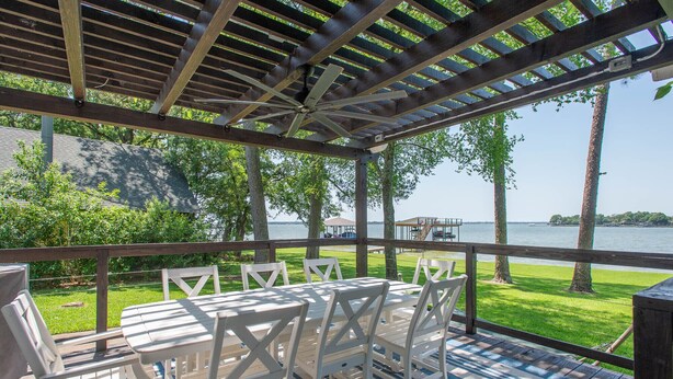 A covered outdoor seating area with a view of the lake. - Stunning Five Bedroom Escape - Great Water! (Enchanted Oaks)