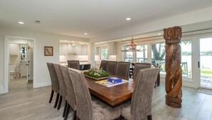 A spacious dining area with a wooden table and upholstered chairs, a chandelier, and a view of the outdoors. - Stunning Five Bedroom Escape - Great Water! (Enchanted Oaks)