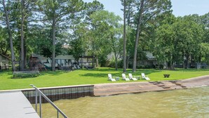 A swimming pool with a deck and lounge chairs, surrounded by trees and a grassy area with a playground. - Stunning Five Bedroom Escape - Great Water! (Enchanted Oaks)