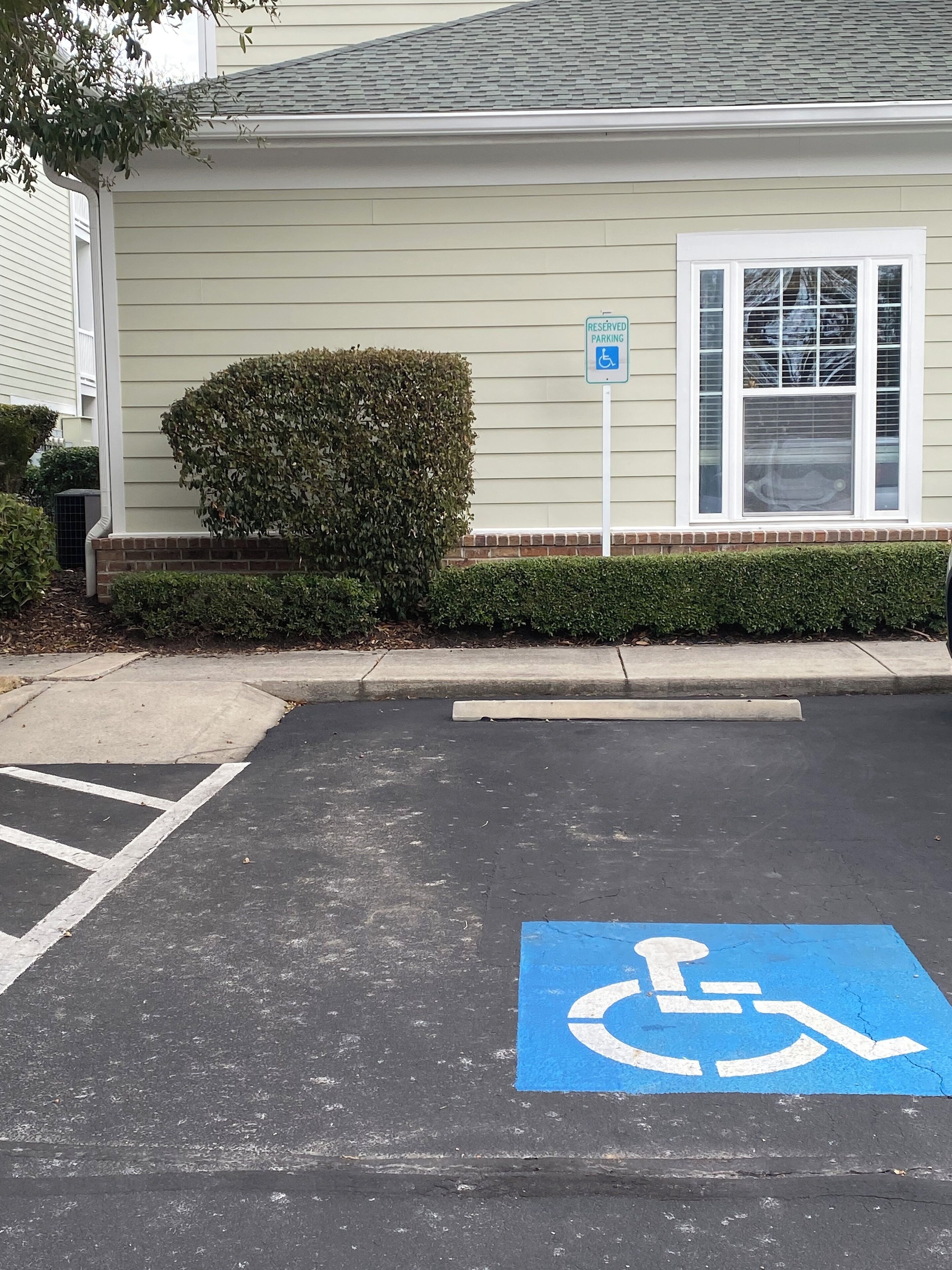 A parking area with a blue handicapped parking sign and a blue handicapped parking space.