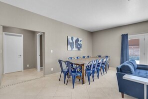 A dining area with a wooden table and blue chairs, a blue sofa, and a painting on the wall. - 8drm • Strip Views• 21 Beds • Free Spa Heat • Basketball (Las Vegas)