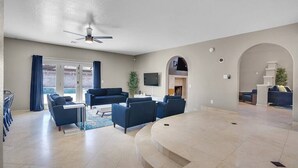 A spacious living area with a curved seating arrangement, a ceiling fan, and a large TV mounted on the wall. - 8drm • Strip Views• 21 Beds • Free Spa Heat • Basketball (Las Vegas)