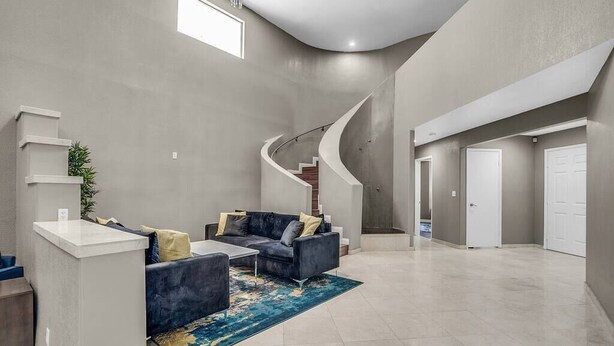 A spacious living area with a curved staircase, a dark blue sofa set, and a light-colored rug. - 8drm • Strip Views• 21 Beds • Free Spa Heat • Basketball (Las Vegas)