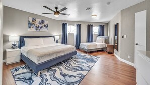 A bedroom with a bed, a nightstand, a ceiling fan, and a window with curtains. - 8drm • Strip Views• 21 Beds • Free Spa Heat • Basketball (Las Vegas)
