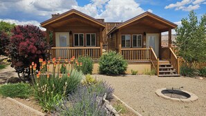 A two-story wooden cabin with a porch, surrounded by landscaped gardens and a clear sky. - Canyons of Escalante RV Park (Escalante)