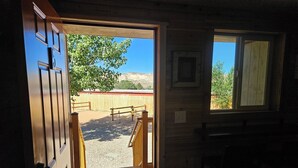 A wooden door leading to a covered outdoor area with a gravel path, a wooden fence, and a clear blue sky. - Canyons of Escalante RV Park (Escalante)