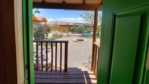 A wooden deck with a metal railing, leading to a covered outdoor area with a fire pit and seating. - Canyons of Escalante RV Park (Escalante)