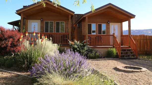 A wooden cabin with a covered porch and a fire pit. - Canyons of Escalante RV Park (Escalante)