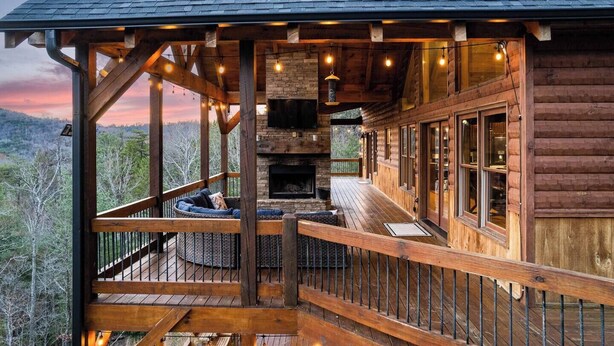 A wooden cabin with a fireplace, a deck with seating, and a view of the surrounding landscape. - Rustic Sunsets - Mountain Views, Hot tub, Arcade, Pool, Central, Aska Adventure (Blue Ridge)