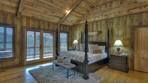 A four-poster bed with a wooden headboard, a bench, and two bedside tables with lamps. - Rustic Sunsets - Mountain Views, Hot tub, Arcade, Pool, Central, Aska Adventure (Blue Ridge)