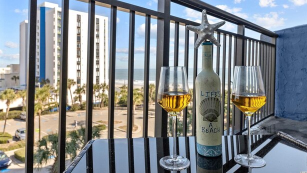 A balcony with a starfish decoration, a bottle of wine, and two glasses of wine. - Beachfront Condo, sleeps 6, pools, hot tub, tiki bar, golf carts allowed (Myrtle Beach)