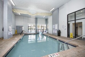 An indoor swimming pool with clear signage, a tiled floor, and a view of the outside. - Bluewater Resort Beachfront Condo  overlooking the sea, pools, hot tub (Myrtle Beach)