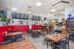 A restaurant interior with tables, chairs, a counter, and a menu board.