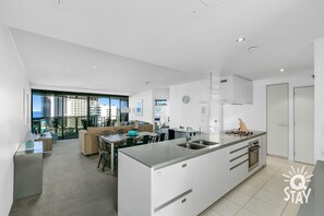 Une cuisine moderne dotée d’un îlot central, d’un four encastré et d’une grande fenêtre donnant sur un paysage urbain.