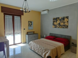 Une chambre à coucher avec un lit, un bureau, une chaise, une commode et un tableau accroché au mur.
