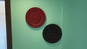 Eine türkisblaue Wand mit zwei runden Wanddekorationen, eine rot und eine schwarz.