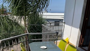Ein Balkon mit Tisch und Stühlen, einer Brüstung und Blick auf das Meer.