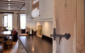A kitchen with wooden cabinets, a stainless steel countertop, and a hanging pot rack. - No. 3 The Forge, village cottage in quiet location with walks from the door (Coniston)