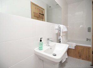 A bathroom with a white sink, a wooden door, and a shower area. - No. 3 The Forge, village cottage in quiet location with walks from the door (Coniston)