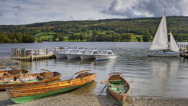 Eine Seeanlegestelle mit mehreren Booten, darunter ein Segelboot, Holzruderbote und Motorboote.