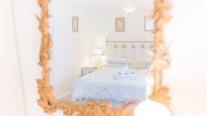 Een slaapkamer met een bed, nachtkastje, lamp en een wandlamp.