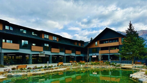Un bâtiment moderne doté d’une cour intérieure avec une piscine à eau claire et des allées pavées de pierres.
