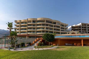 A multi-story hotel with a curved facade, outdoor seating area, and a tennis court. - Mexico El Dorado 203 (Ajijic)