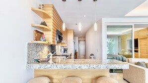 Una cocina moderna con encimera de granito, taburetes de madera y estanterías empotradas.