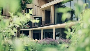 Un edificio moderno con un amplio ventanal de vidrio, un balcón y un jardín.