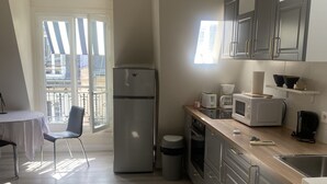 Eine moderne Küche mit Kühlschrank, Mikrowelle und Spüle. Es gibt einen Essbereich mit Tisch und Stühlen.