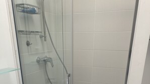 Eine begehbare, gläserne Dusche mit Handbrause und Wandarmatur.
