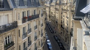 Eine schmale Straße, gesäumt von mehrstöckigen Gebäuden mit Balkonen und parkenden Autos.