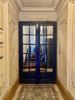 A grand entrance with a dark blue door, a tiled floor, and a marble wall.