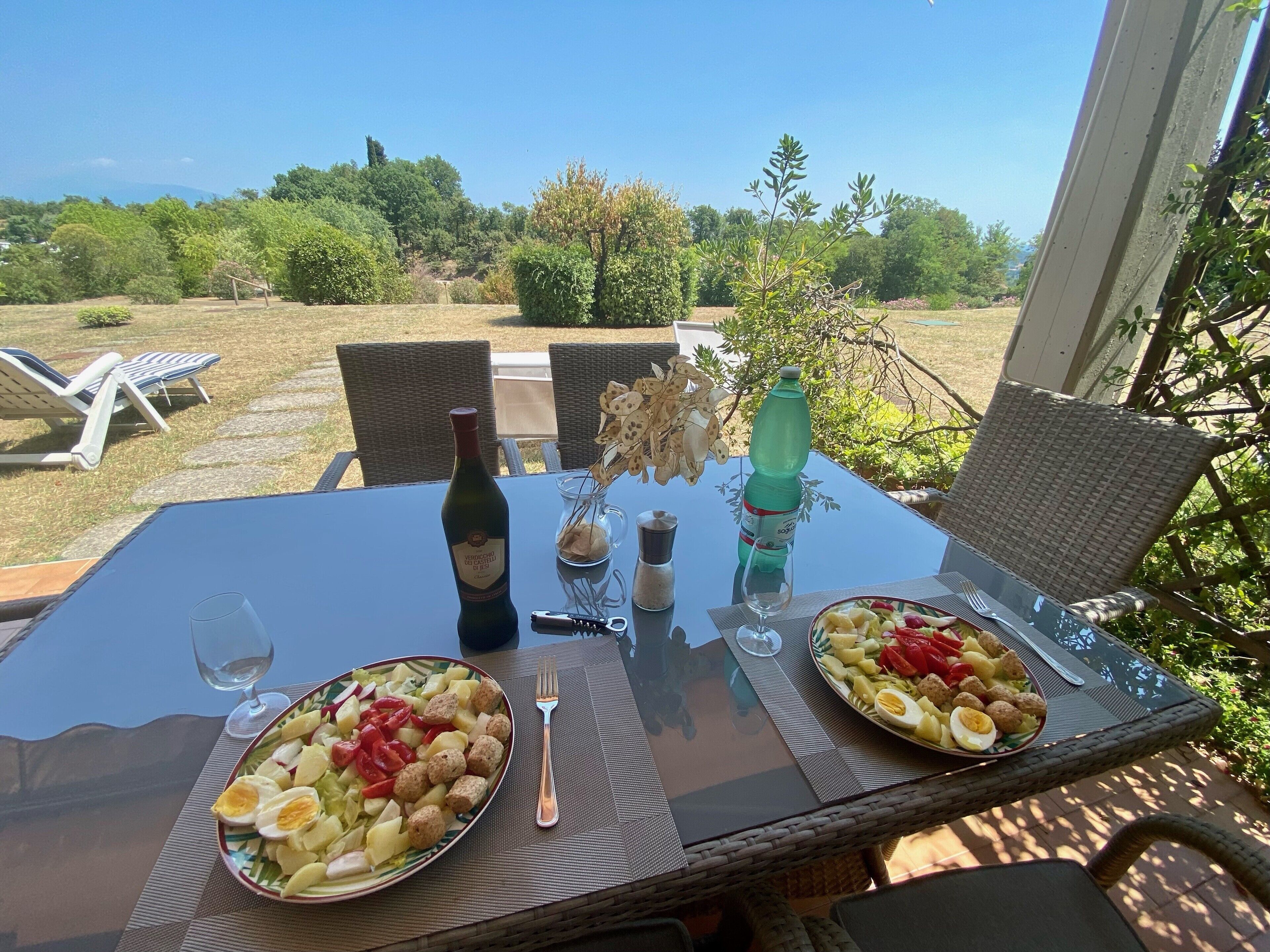 Ein Esstisch mit zwei Teller Essen, einer Weinflasche und einem Wasserglas.