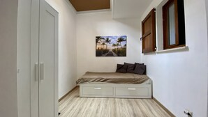 Ein Schlafzimmer mit Bett, Kleiderschrank, Oberlicht, einem Gemälde und einem Fenster.