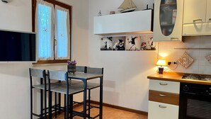 Eine kompakte Küche mit Essbereich, einem Fernseher und einem kleinen Regal mit Dekoration.