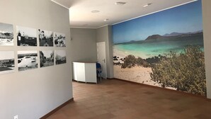 A room with a large mural of a beach scene, a reception desk, and several black-and-white photographs on the wall.